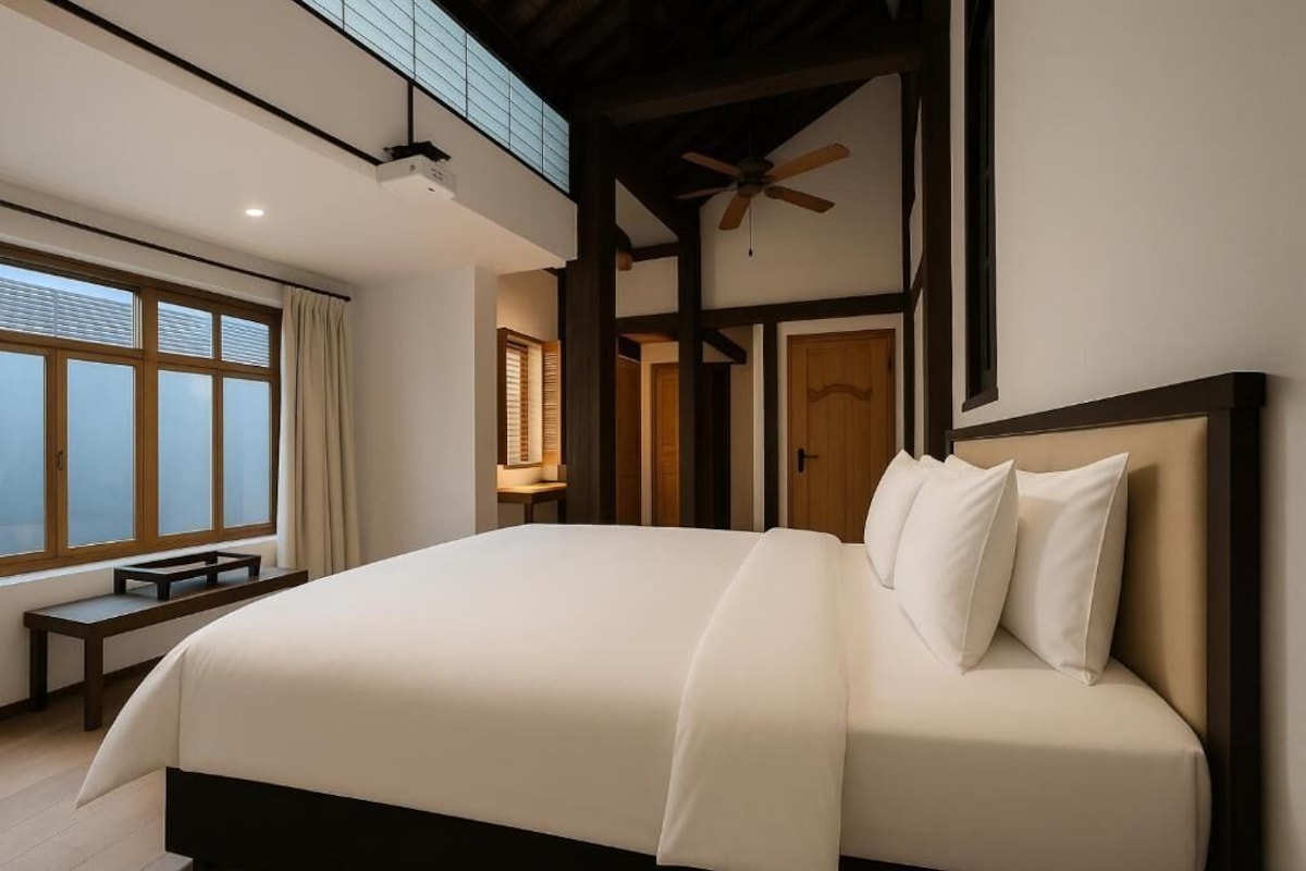 A modern bedroom with a large bed, a ceiling fan, and a view through a window.