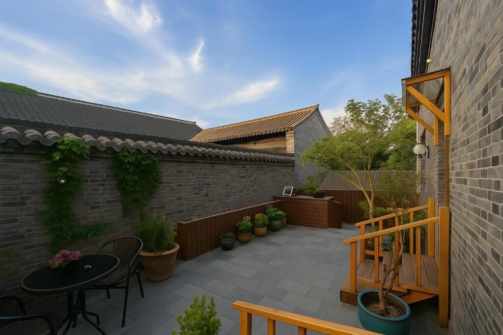 A courtyard with a brick wall, a wooden bench, a table, and potted plants.