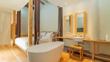 Ein modernes Hotelzimmer mit einer großen Badewanne, einem Bett, einer hölzernen Bank und einem kleinen Tisch mit einem Spiegel.