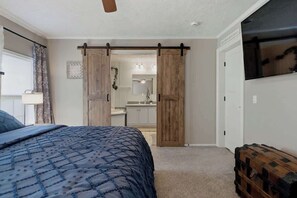 Ein Schlafzimmer mit einem Bett, einem Schiebetürenschrank, einem Fernseher und einem Koffer.