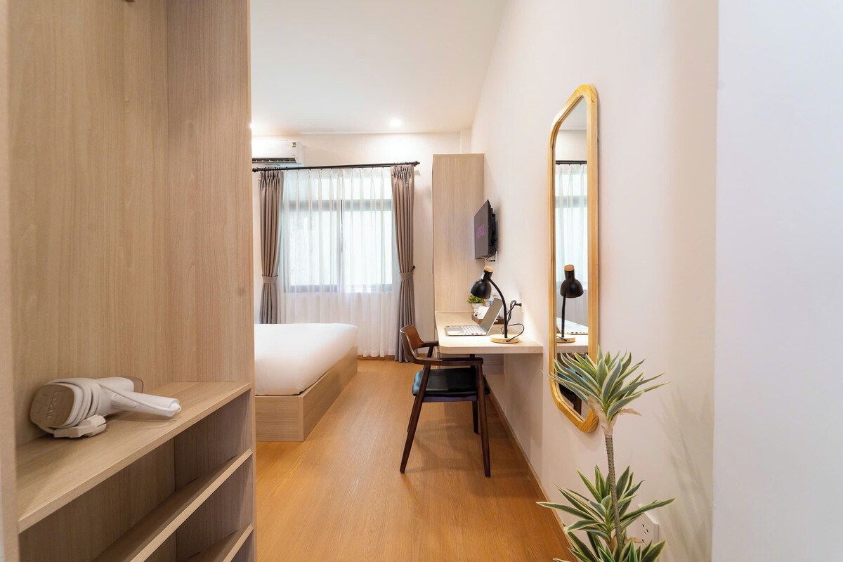 Una habitación de hotel con cama, escritorio, silla y espejo.