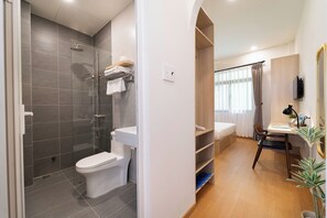 Uma casa de banho moderna com chuveiro, sanita e lavatório.