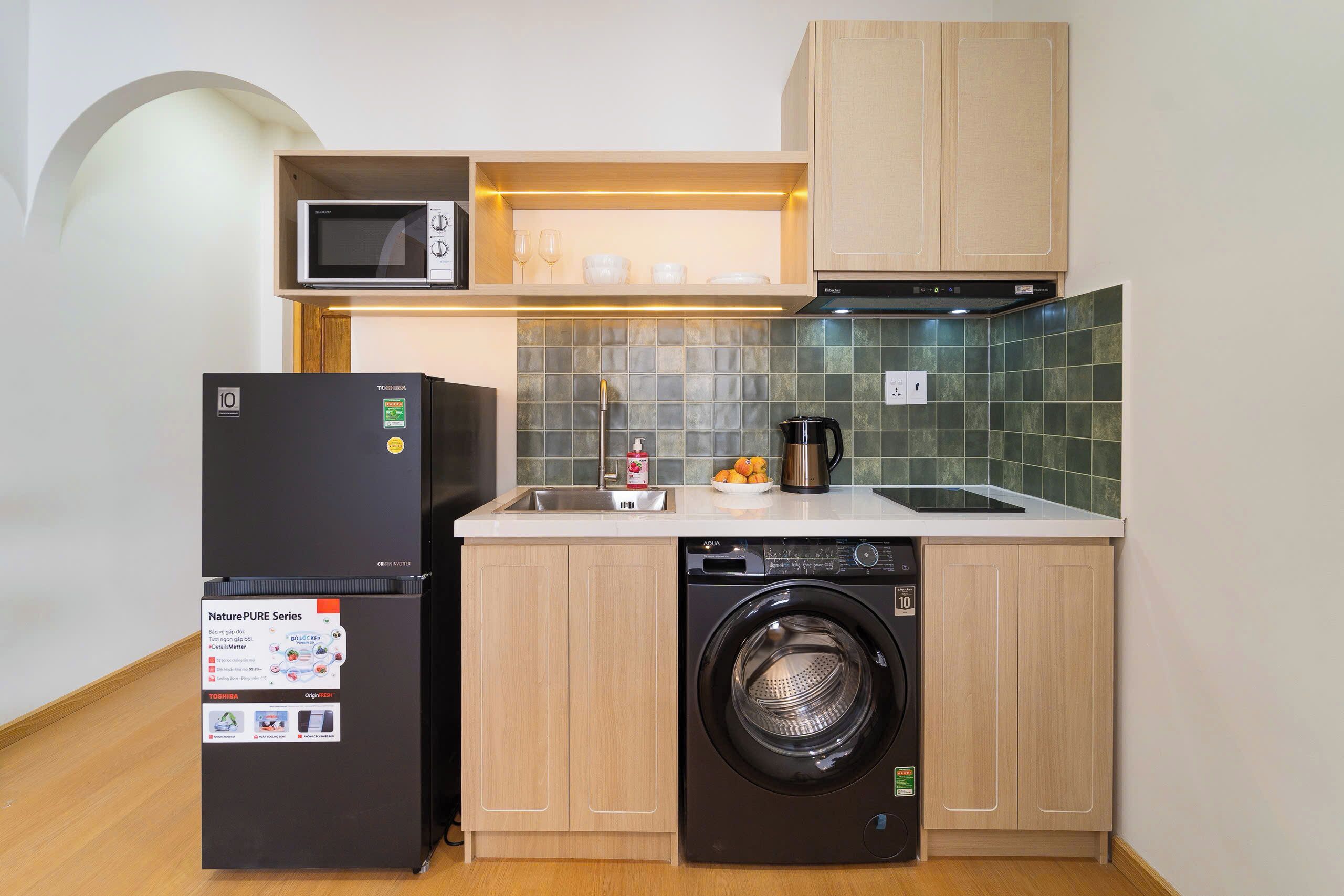 A compact kitchen with a refrigerator, microwave, dishwasher, and washing machine.