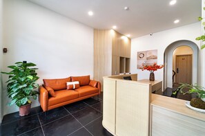 Un área de recepción con un mostrador de madera, un sofá de cuero y plantas en macetas.