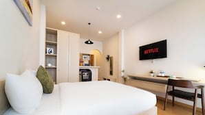 A hotel room with a bed, a desk, a TV, and a kitchenette. - SORA HOTEL & APARTMENT (Ho Chi Minh City)