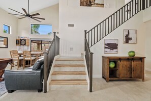 Ein geräumiger Wohnbereich mit Treppe, Esstisch und einer Couch.