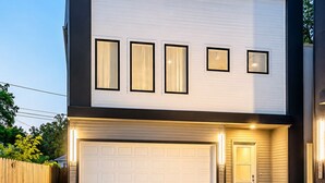 Une maison moderne à deux étages, dotée d’un garage, d’une clôture en bois et d’une allée.