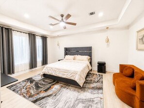A modern bedroom with a bed, a ceiling fan, a nightstand, a sofa, and a marble-patterned rug. - Comfort & luxury in Houston! 3 bedrooms, near NRG stadium, TMC, and downtown (Houston)
