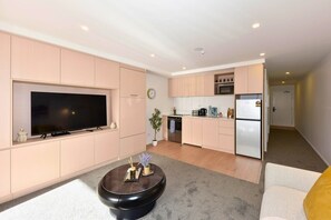 Un appartement moderne doté d’une télévision à écran plat, d’un coin repas, d’une cuisine avec réfrigérateur et d’un salon avec une table basse.