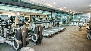 Une salle de sport équipée de tapis de course, d’elliptiques et de vélos d’exercice.