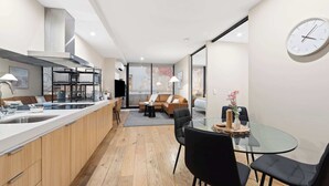 Une cuisine moderne dotée d’un îlot central, un coin repas avec une table en verre et un espace de vie comprenant un canapé et une table basse.