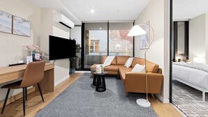 Une chambre d’hôtel moderne équipée d’un bureau, d’un canapé et d’un lit, d’un téléviseur à écran plat et d’une grande fenêtre.