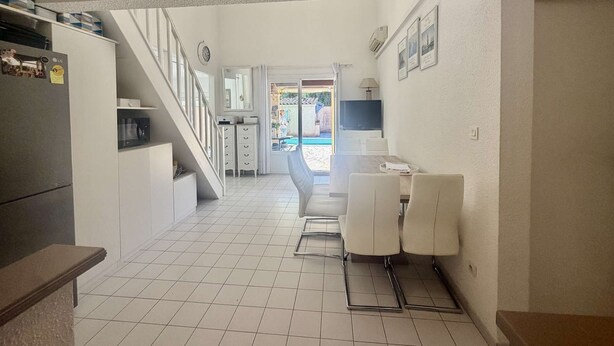 A kitchen with a refrigerator, cabinets, and a dining area with chairs and a table. - CHARMING HOUSE WITH PRIVATE SWIMMING POOL FOR 6 PEOPLE (STE MAXIME)