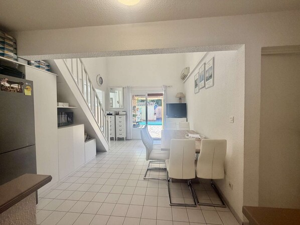 Eine Küche mit Kühlschrank, Schränken und einem Essbereich mit Stühlen und Tisch.