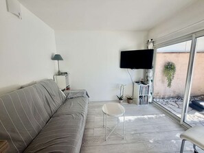 Ein modernes Wohnzimmer mit einer Couch, einem kleinen Tisch, einem Fernseher und einem Bücherregal.