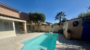 A swimming pool with a stone deck, surrounded by a house with a tiled roof and a palm tree. - CHARMING HOUSE WITH PRIVATE SWIMMING POOL FOR 6 PEOPLE (STE MAXIME)