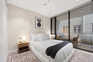 Ein modernes Hotelzimmer mit einem großen Bett, einem Nachttisch mit Lampe, einem Wandbild und einem Balkon mit Blick.