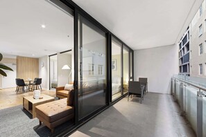 Eine moderne Wohnung mit Wohnbereich, Essplatz und einem Balkon mit Geländer.