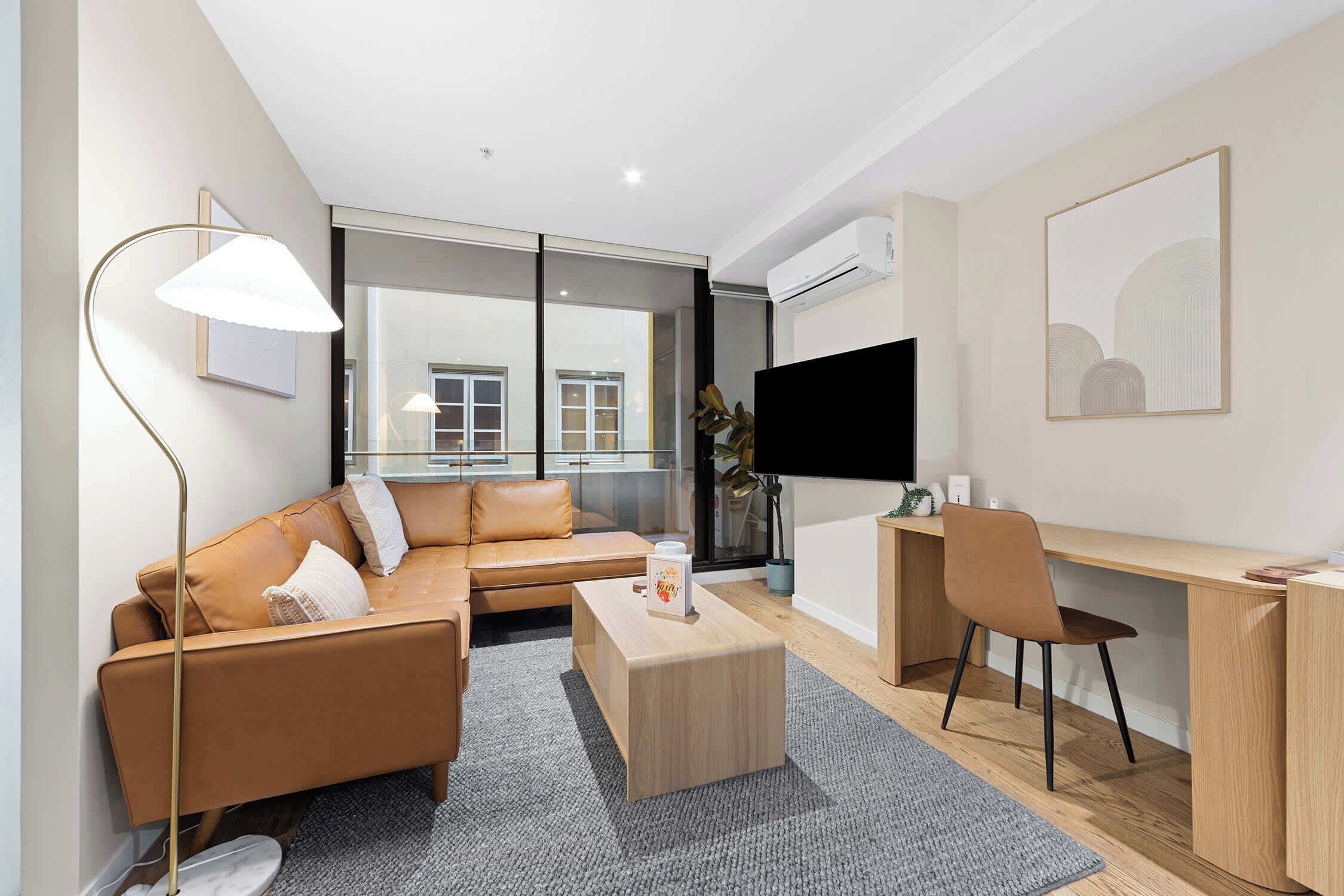 A modern living room with a sofa, a coffee table, a desk, and a chair.