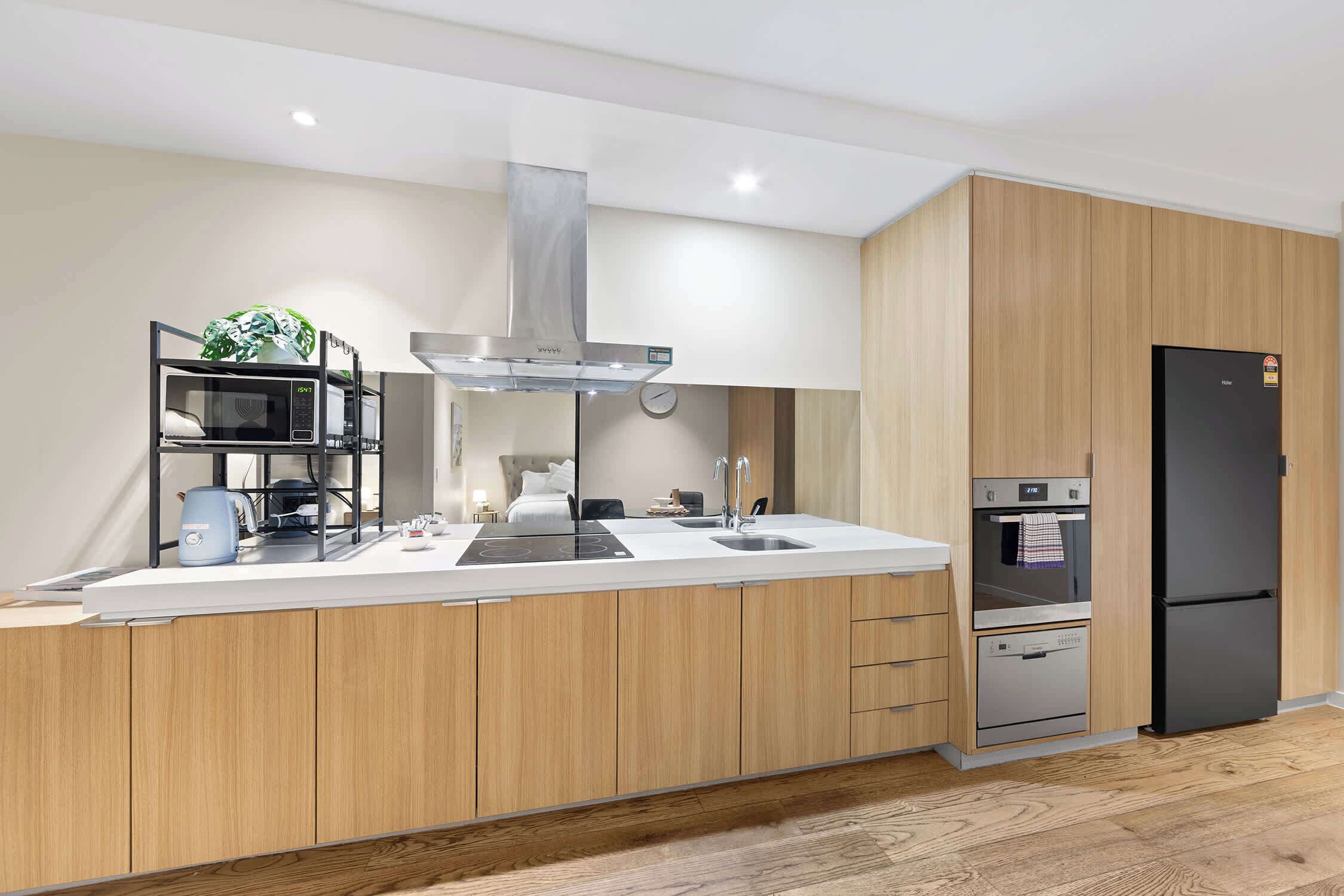 Une cuisine moderne équipée d’un four à micro-ondes, d’une cuisinière et d’un four encastrés, de meubles de rangement en bois et d’un réfrigérateur noir.