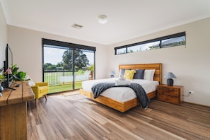 A bedroom with a large bed, a desk, a chair, and a view of a balcony. - Golf Course Views & Short Walk to Town (Dunsborough)