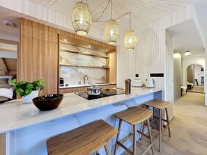 Eine moderne Küche mit Marmorarbeitsplatte, Holzelementen und Pendelleuchten.