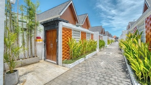 Een woonstraat met huizen, een verhard voetpad en groen.