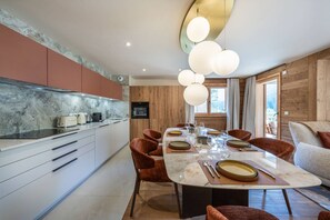 A modern kitchen with a marble countertop, wooden cabinets, and a dining area with a marble table and red chairs. - ETOILES DU LINGA  - A22 (CHATEL)