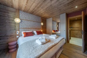 Ein Schlafzimmer mit Holzwänden, einem großen Bett, zwei Nachttischlampen und einem Spiegel.
