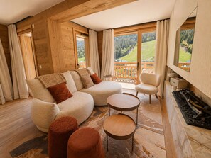 Ein gemütliches Wohnzimmer mit einem Ecksofa, Poufs, einem Couchtisch und einem Kamin.