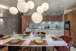 A modern kitchen with marble countertops, a dining area with a large table set for six, and pendant lighting. - ETOILES DU LINGA  - A22 (CHATEL)