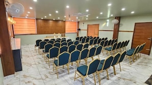 A conference room with rows of chairs, a podium, and a cross on the wall.