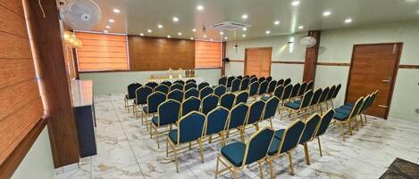 A conference room with rows of chairs, a podium, and a cross on the wall.