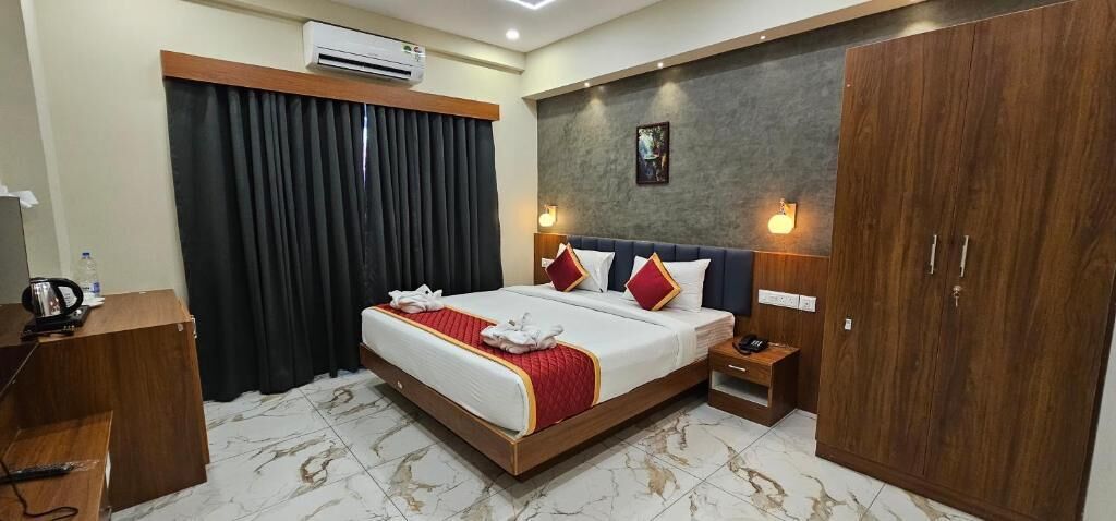 Quarto de hotel com uma cama grande, um guarda-roupa, uma mesa de cabeceira, uma escrivaninha e uma cortina.