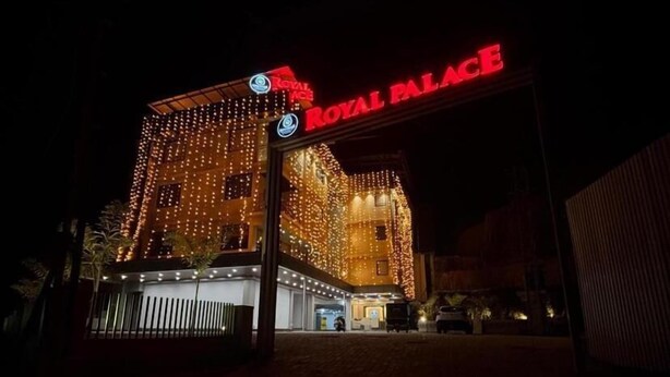 A building with a prominent 'Royal Palace' sign, multiple windows, and a gated entrance.