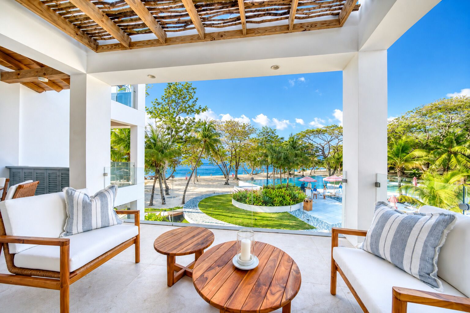Un espace extérieur moderne, aménagé avec du mobilier en bois et offrant une vue sur une piscine et une plage.