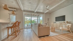 Una sala de estar moderna con un sofá, sillas, un televisor y vistas al exterior.
