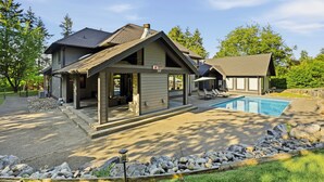 A two-story house with a covered porch, a swimming pool, and a stone pathway.