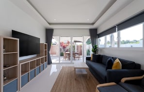 Una sala moderna con televisor de pantalla plana, un sofá, una mesa de centro y vista al patio exterior.