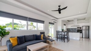 A modern living room with a sofa, coffee table, and dining area. - Orchid Paradise Homes OPV422 (Hin Lek Fai)