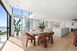 Ein modernes Interieur mit Essbereich, Kücheninsel und großen Fenstern mit Aussicht.