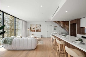 Eine moderne Küche mit weißer Arbeitsplatte, Holzstühlen und einer Treppe.