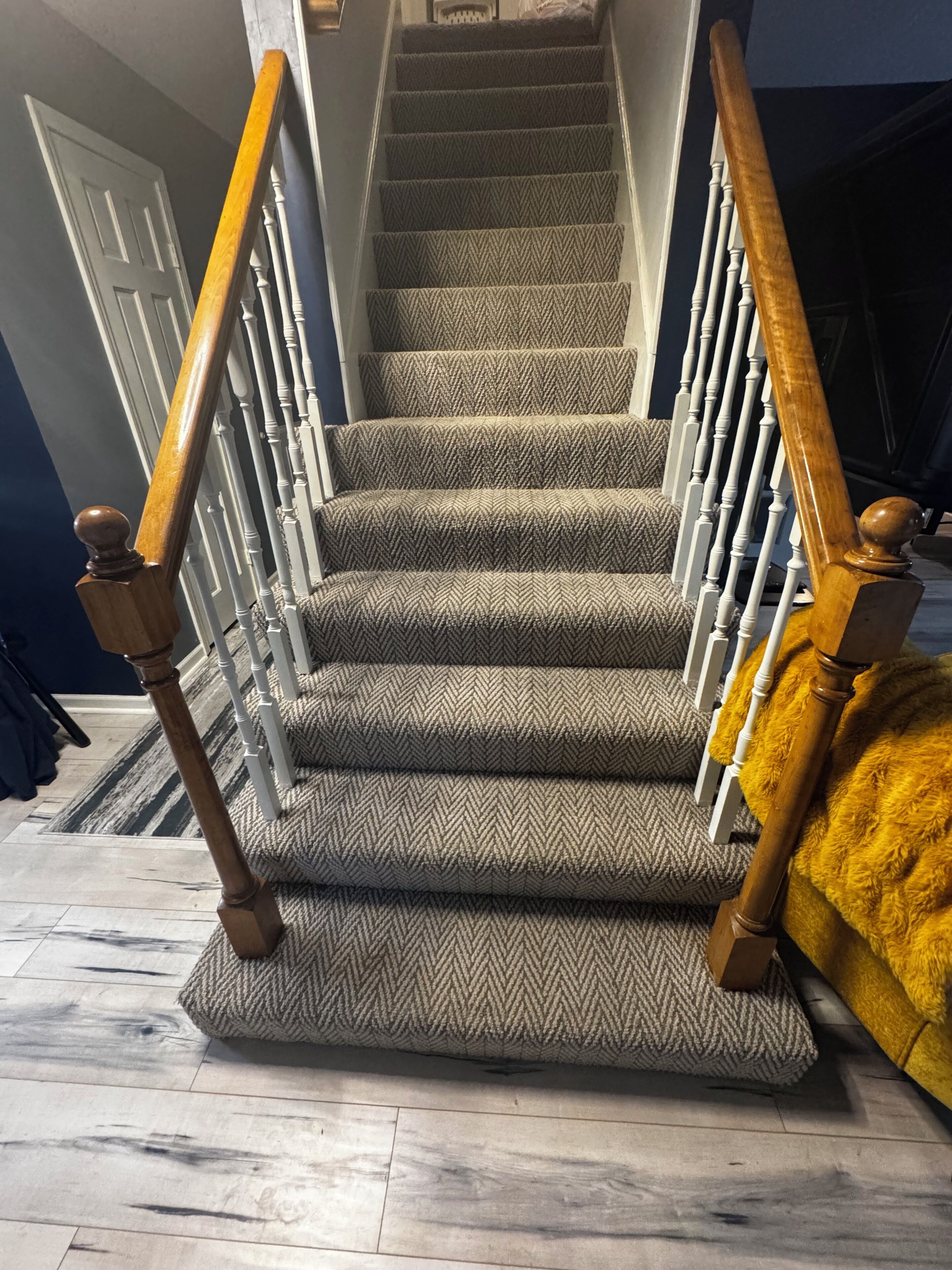 A carpeted staircase with wooden handrails and a patterned carpet.