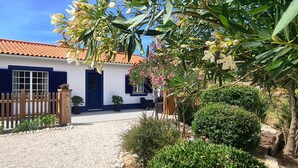 Une maison avec un toit en tuiles, une allée en gravier et un portail en bois.
