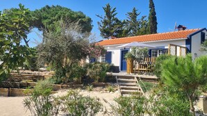 Une maison avec un toit recouvert de tuiles rouges, une porte bleue et un mur extérieur blanc.