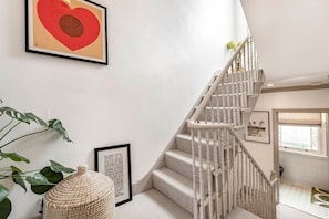 A staircase with white balusters, a framed heart artwork, and a plant. - Stylish Chelsea Home Amazing Location (London)
