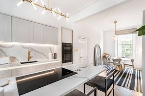 A modern kitchen with white cabinetry, a black countertop, and a stainless steel refrigerator. - Stylish Chelsea Home Amazing Location (London)