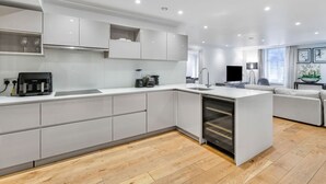 Una cucina moderna con mobili bianchi, forno integrato e un'isola grande con lavello.