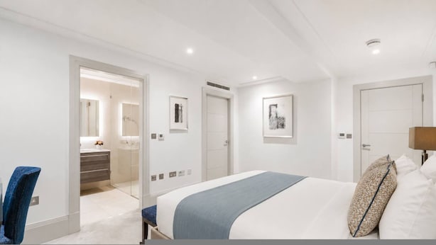 Una camera d'albergo moderna con un letto, una scrivania, una sedia, un bagno e opere d'arte alle pareti.
