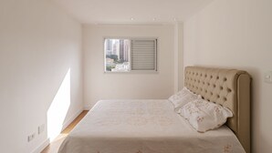 A bedroom with a bed, a window with blinds, and a view of buildings. - Ap Bela Vista c Portaria 24h Paulista e Masp (São Paulo)